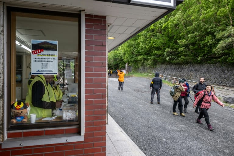 Des randonneurs passent devant le centre administratif de la 5e station de la ligne Fuji Subaru, qui mène au sentier Yoshida pour l'ascension du mont Fuji, le premier jour de la saison avec les nouvelles mesures de droits d'entrée, le 1er juillet 2024 à Narusawa, au Japon. (Philip FONG)