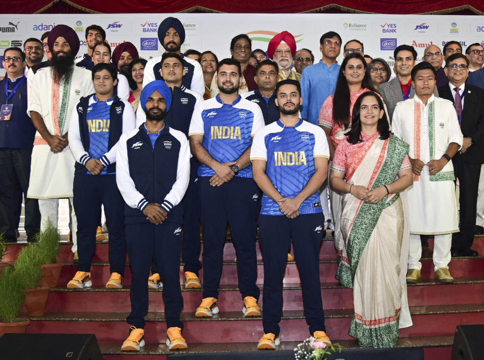 Esta imagen compartida por la Oficina de Información Pública muestra atletas indios posando con funcionarios mientras modelan los uniformes ceremoniales y de competencia de la India para los Juegos Olímpicos de París en Nueva Delhi, India, el domingo 30 de junio de 2024. (Press Information Bureau vía AP)