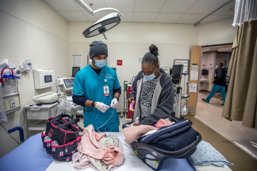 Los Angeles, CA - January 02: Latoya Hawkins, right, brought her four-month-old daughter Aroyal Collier, (CQ) middle, into the Emergency Department at MLK Community Hospital on Monday, Jan. 2, 2023, in Los Angeles, CA. The hospital EMT is checking Aroyal's vitals. (Editor's warning: Child. No Sales.) (Francine Orr / Los Angeles Times)