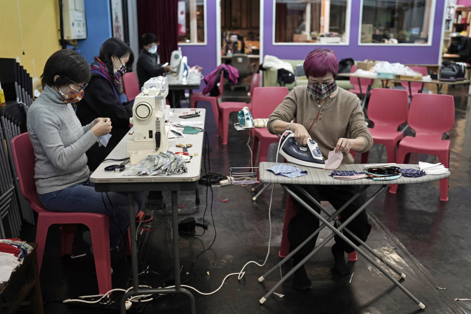 In this Monday, Feb. 17, 2020, photo, volunteers make the handmade cotton masks in Hong Kong. Volunteers from a Hong Kong theater group are turning their backstage skills to helping out against the new coronavirus, sewing reusable protective masks for those who can't access or afford them. Jo Ngai, a drama lover and founder of the Nonsensemakers, along with her friend Jessie Han, have turned a theater rehearsal room into a temporary handmade mask factory. (AP Photo/Kin Cheung)