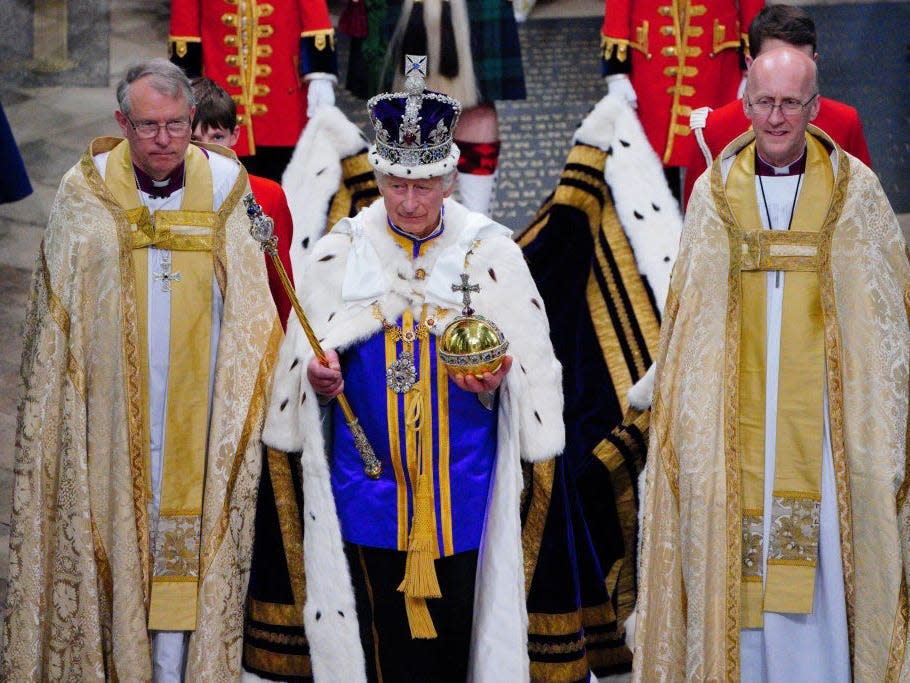 King Charles leaves Westminster Abbey after the coronation, wearing the Imperial State Crown and Estate Robes.