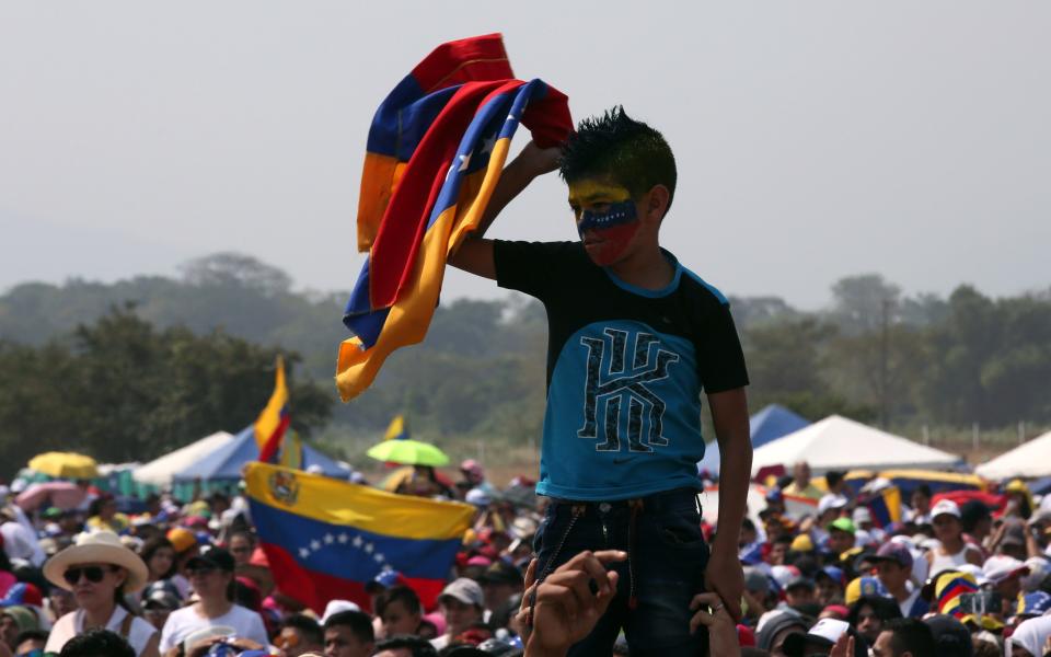 <p>CC01. CÚCUTA (COLOMBIA), 22/02/2019.- Un niño sostiene una bandera venezolana durante el concierto Venezuela Aid Live este viernes, en el puente fronterizo de Tienditas, en Cúcuta (Colombia). El concierto “Venezuela Aid Live”, que fue convocado por el multimillonario Richard Branson, comenzó en el lado colombiano del puente fronterizo de Tienditas con el himno nacional de Colombia y entre los aplausos de los miles de personas que acudieron a la cita. La convocatoria, que fue respondida por 32 artistas de una decena de países, tiene como objetivo impulsar la ayuda humanitaria para apoyar a los venezolanos afectados por la crisis en su país y recaudar 100 millones de dólares para los más necesitados. EFE/Mauricio Dueñas Castañeda </p>