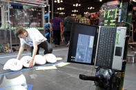 A volunteer setting piles of discs in place for the next match, as teams wait for their turn to set up the control conoles.