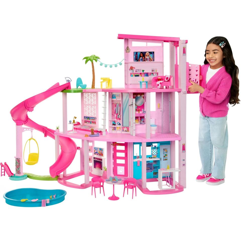 model playing with pink barbie dreamhouse