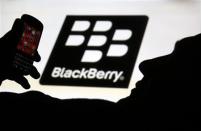 A man is silhouetted against a video screen with the Blackberry logo as he poses with a Blackberry Q10 in the central Bosnian town of Zenica in this September 21, 2013 file photo illustration. REUTERS/Dado Ruvic/Files