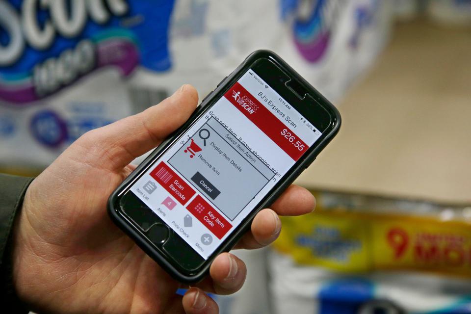 A shopper displays a shop-and-go app on his cell phone at a BJ's Wholesale Club store. Hy-Vee is disabling its Shop & Go system.