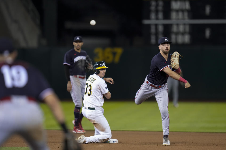 Minnesota Twins second baseman Edouard Julien, right, throws to first next to Oakland Athletics' JJ Bleday, center, to turn a double play against Brent Rooker during the seventh inning of a baseball game Friday, July 14, 2023, in Oakland, Calif. (AP Photo/Godofredo A. Vásquez)