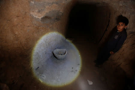 A boy looks at artefacts and archaeological pieces in a tunnel network running under the Mosque of Prophet Jonah, Nabi Yunus in Arabic, in eastern Mosul, Iraq March 9, 2017. REUTERS/Suhaib Salem