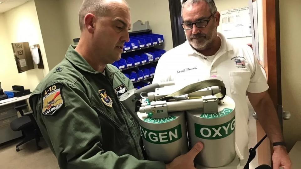 Brig. Gen. Ed Vaughan, the lead for the Air Force Physiological Episodes Action Team, and Gerald Flowers, member of the 12th Flying Training Wing maintenance division, examine an on-board oxygen generating system (OBOGS) from a T-6 aircraft at Randolph Air Force Base, Texas. (Lt. Col. Kyle Goldstein/Air Force)