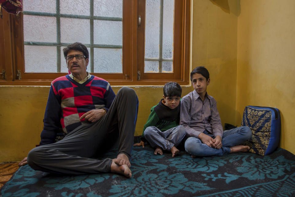 In this March 30, 2017 photo, Mir Mehran, 11, right, a Kashmiri boy who was forced by Indian paramilitary soldiers to perform sit-up while holding his ear lobes, sits with his cousin Saiba Mir and his father Mohammed Qayoom Mir during an interview with The Associated Press at his home in Srinagar, Indian-controlled Kashmir. Seeing Kashmiri residents doing calisthenics on the side of the road was once common in the 1990s, as government forces sought to humiliate people as a way of dissuading any support for armed rebels fighting against Indian rule in the disputed Himalayan territory. As the rebellion was crushed, Indian soldiers mostly stopped using public sit-ups as a form of punishment. (AP Photo/Dar Yasin)
