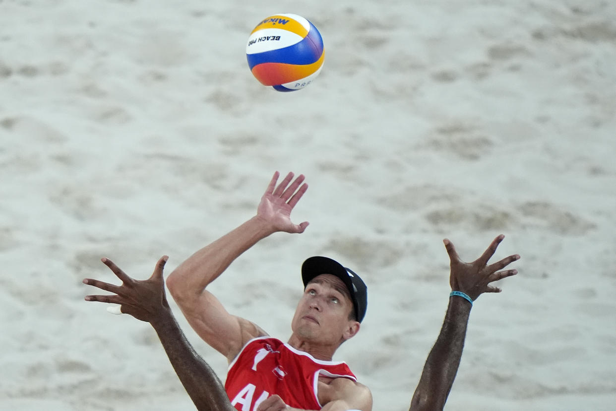 Austria's Alexander Horst hits over the outstretched arms of Brazil's Evandro Goncalves Oliveira Junior in a beach volleyball match.