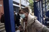 A woman wearing a face mask enters a primary school where a child was diagnosed with coronavirus in the northern city of Thessaloniki, Greece, on Thursday, Feb. 27, 2020. Greece's Health Minister Vassilis Kikilias said all carnival events in Greece would be suspended as a precautionary measure. (AP Photo/Giannis Papanikos)