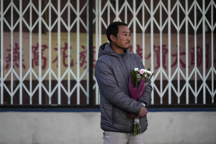 Hunter Zhao, 41, holds flowers to honor the victims killed in Saturday&#39;s mass shooting in Monterey Park, Calif., Sunday. (Jae C. Hong/AP)