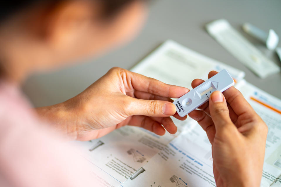 Asian woman using rapid antigen test kit for self test COVID-19 epidemic at home.  Adult female unpacking a swab for inserts into her nose. COVID-19 coronavirus pandemic protection concept.