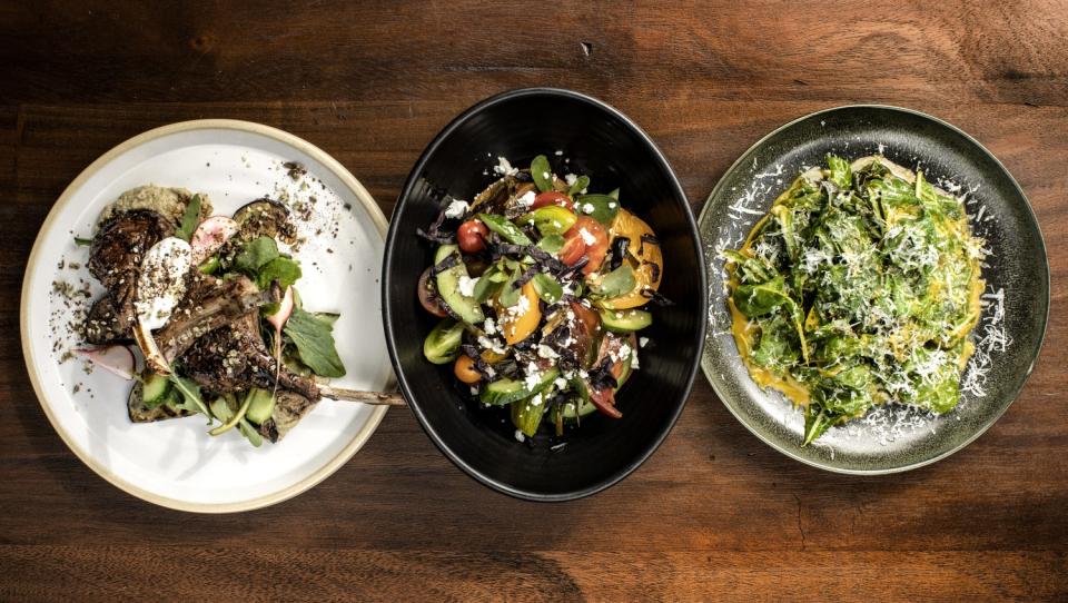 A lineup of plates holding meat and vegetable dishes.