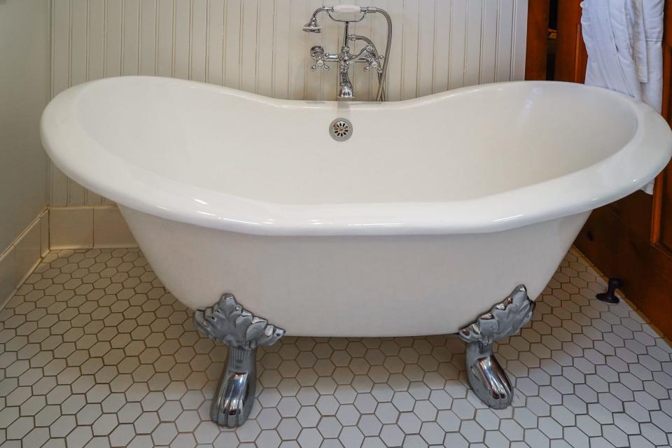 Big, white claw-foot tub with sliver fixtures in a white bathroom