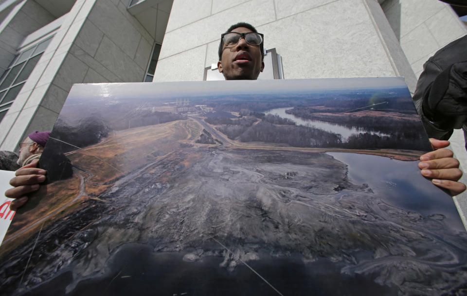Johnny Collins, of Kernersville, N.C., holds a large photo of a Duke Energy coal plant during a protest near Duke Energy's headquarters in Charlotte, N.C., Thursday, Feb. 6, 2014 over Duke Energy's coal plants. Duke Energy estimates that up to 82,000 tons of ash has been released from a break in a 48-inch storm water pipe at the Dan River Power Plant on Sunday. (AP Photo/Chuck Burton)