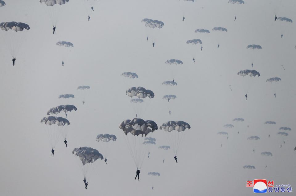 Soldiers are seen parachuting in the sky during a demonstration during the training of the Korean People's Army's air and amphibious combat units.