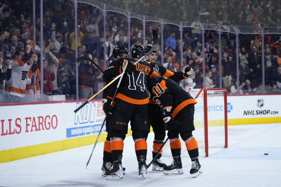 Philadelphia Flyers' Sean Couturier (14) celebrates with teammates after scoring the game-winning goal during overtime in an NHL hockey game against the Vegas Golden Knights, Saturday, Nov. 18, 2023, in Philadelphia. (AP Photo/Matt Slocum)