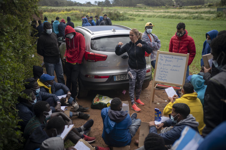 A resident from Tenerife teaches Spanish to migrants from different nationalities outside Las Raices camp in San Cristobal de la Laguna, in the Canary Island of Tenerife, Spain, Saturday, March 20, 2021. While Spain has been critical of its European neighbours' lack of solidarity when it comes to sharing the responsibility of migration, the country is similarly being criticized by migrants, authorities and human rights organizations on the Canary Islands where some 23,000 people arrived by sea last year and where many thousands remain on the island forcefully. (AP Photo/Joan Mateu)