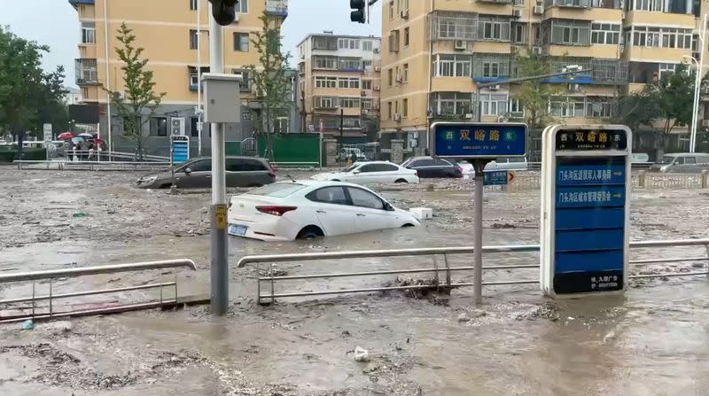 Water gushes on a flooded street following Typhoon Doksuri in Beijing