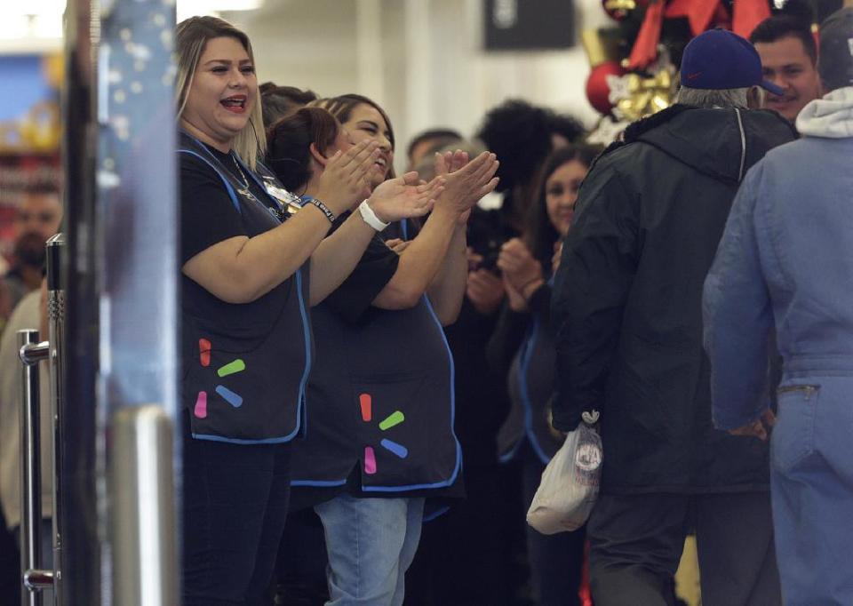 Walmart employees cheer to welcome customers during the store’s opening.