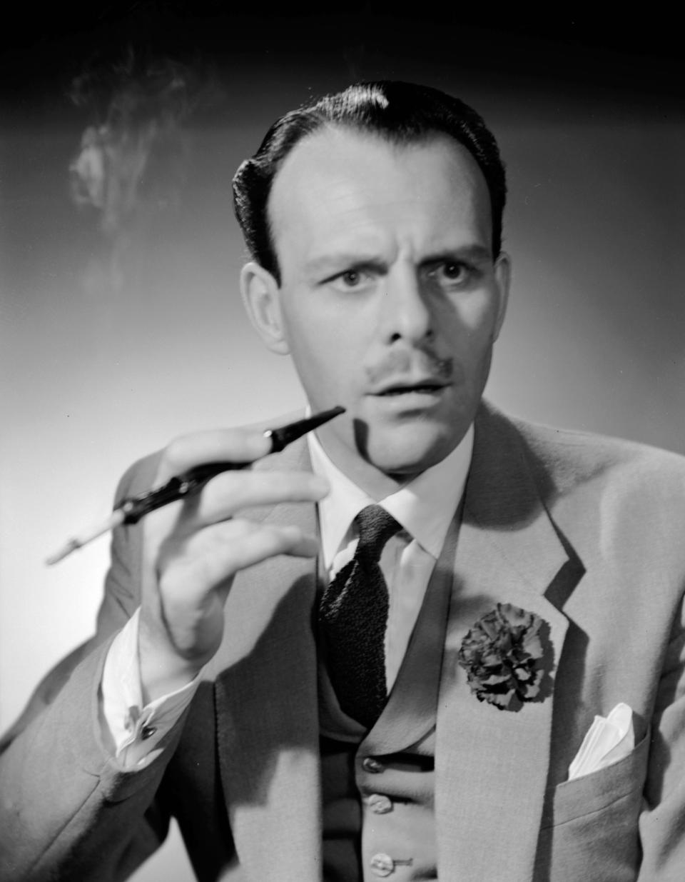 1951:  English actor-comedian Terry Thomas (1911 - 1990), real name Thomas Terry Hoar-Stevens, smoking a cigarette in a long holder.  (Photo by Denis De Marney/Getty Images)