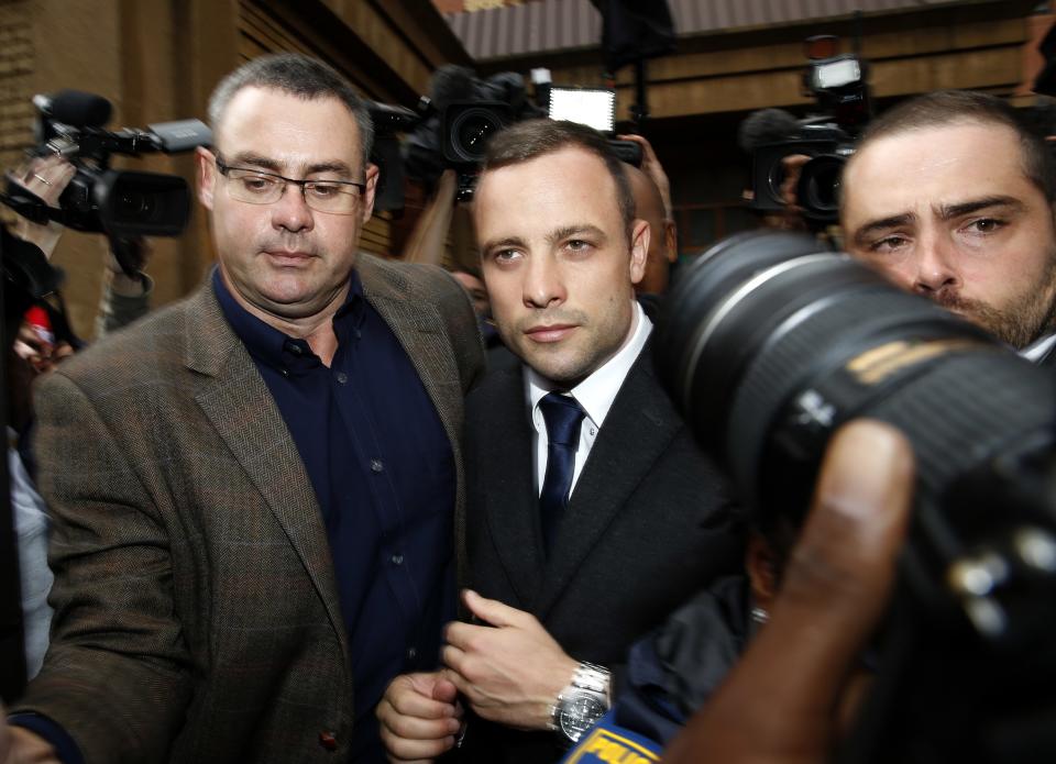 Members of the media photograph Olympic and Paralympic track star Oscar Pistorius (C) as he leaves after his trial at the North Gauteng High Court in Pretoria March 4, 2014. Pistorius is on trial for murdering his girlfriend Reeva Steenkamp at his suburban Pretoria home on Valentine's Day last year. He says he mistook her for an intruder. REUTERS/Siphiwe Sibeko (SOUTH AFRICA - Tags: CRIME LAW MEDIA SPORT ATHLETICS)