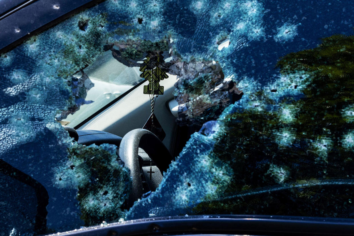 A rosary is seen through a damaged vehicle window (Chris Machian / Omaha World-Herald via AP)