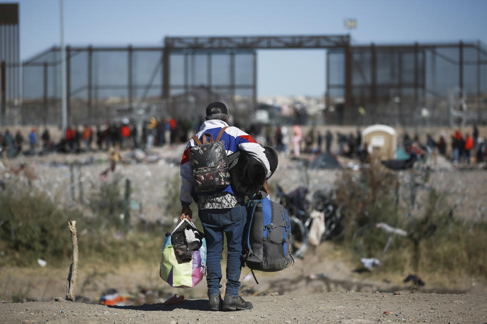 Migrantes carga varias mochilas mientras se dirige hacia la barrera en entrada de la frontera con Estados Unidos desde Ciudad Juárez, México, el 27 de diciembre de 2023. (AP Foto/Christian Chávez)