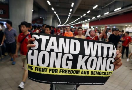A demonstrator holds a sign in support of anti-government protesters at a football World Cup qualifier match between Hong Kong and Iran, at Hong Kong Stadium