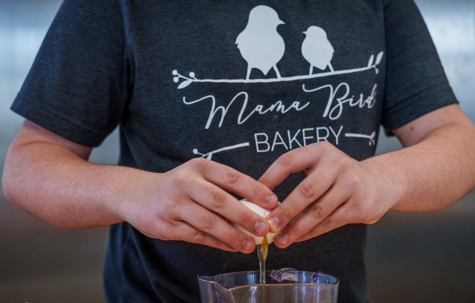 Owen Carr cracks an egg Saturday, Feb. 4, 2023, while preparing dough inside the kitchen at Mama Bird Bakery in Plainfield, Indiana.