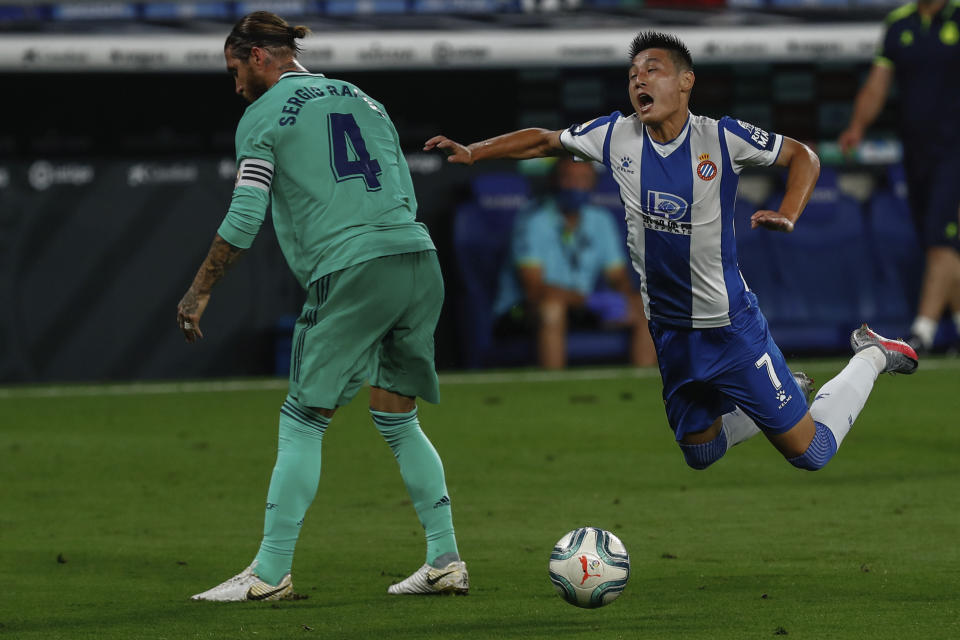 Espanyol's Wu Lei, right, is tackled by Real Madrid's Sergio Ramos during the Spanish La Liga soccer match between RCD Espanyol and Real Madrid at the Cornella-El Prat stadium in Barcelona, Spain, Sunday, June 28, 2020. (AP Photo/Joan Monfort)