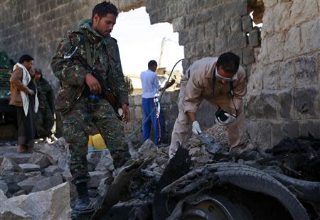 Investigators from the criminal investigation department (CID) examine the wreckage of a car after a bomb exploded outside the main wall of the central prison in Sanaa February 14, 2014. REUTERS/Mohamed al-Sayaghi