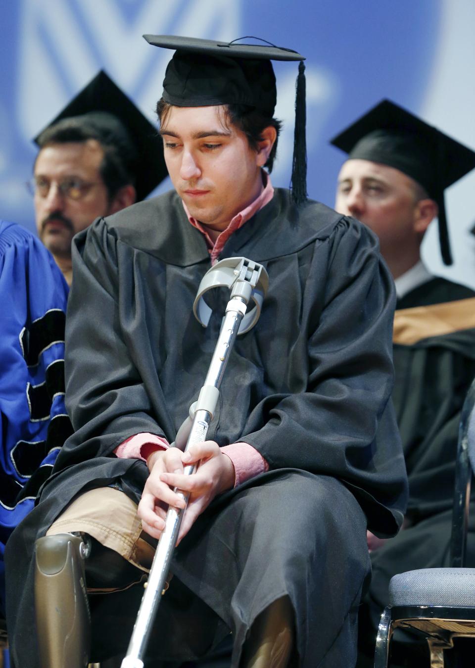 Boston Marathon bombing survivor Jeff Bauman listens as Carlos Arredondo gives his commencement address during graduation ceremonies for Fisher College in Boston, Saturday, May 10, 2014. Bauman and Arredondo each gave graduation speeches and were awarded honorary degrees during the ceremony. (AP Photo/Michael Dwyer)