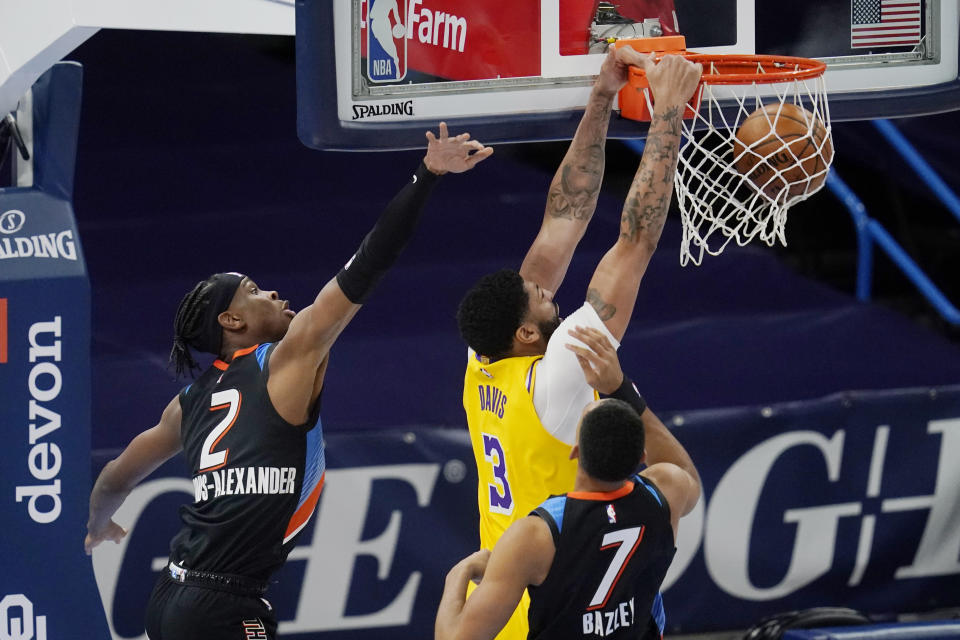 Los Angeles Lakers forward Anthony Davis (3) dunks in front of Oklahoma City Thunder guard Shai Gilgeous-Alexander (2) and forward Darius Bazley (7) during the first half of an NBA basketball game Wednesday, Jan. 13, 2021, in Oklahoma City. (AP Photo/Sue Ogrocki)