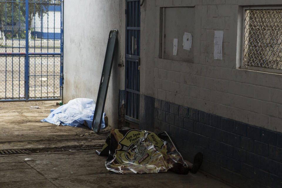 Two covered bodies lie inside the entrance area of the Pavon Rehabilitation Model Farm as authorities try to take control of the jail after a shooting in Fraijanes, Guatemala, Tuesday, May 7, 2019. At least three people were killed and 10 people were wounded in the shooting, authorities said. (AP Photo/Oliver De Ros)