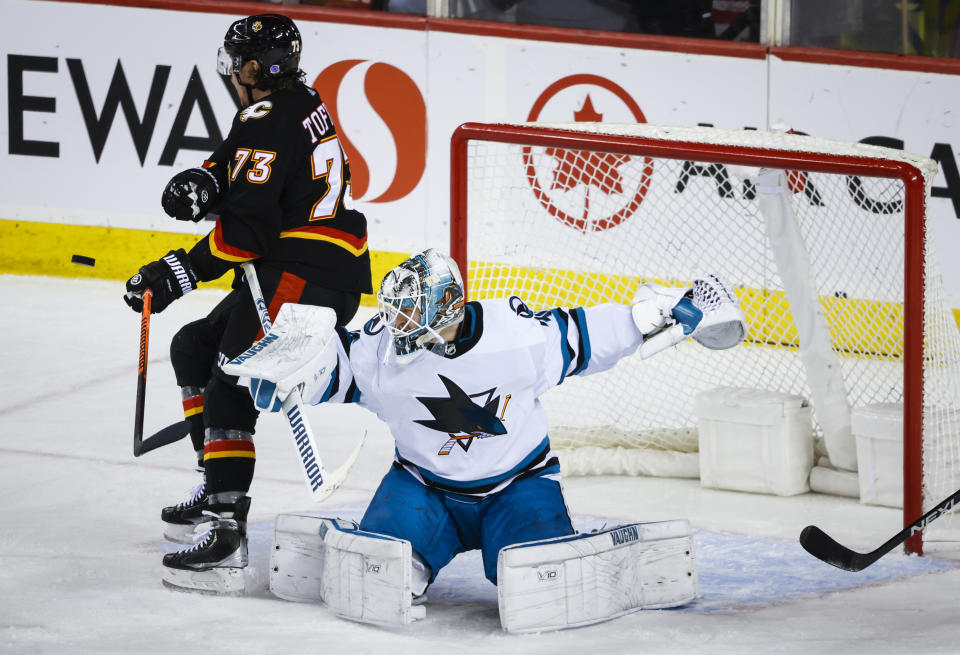 San Jose Sharks goalie Kaapo Kahkonen, right, shoves Calgary Flames forward Tyler Toffoli away from the net as he tries to deflect a shot during the second period of an NHL hockey game in Calgary, Alberta, Saturday, March 25, 2023.(Jeff McIntosh/The Canadian Press via AP)