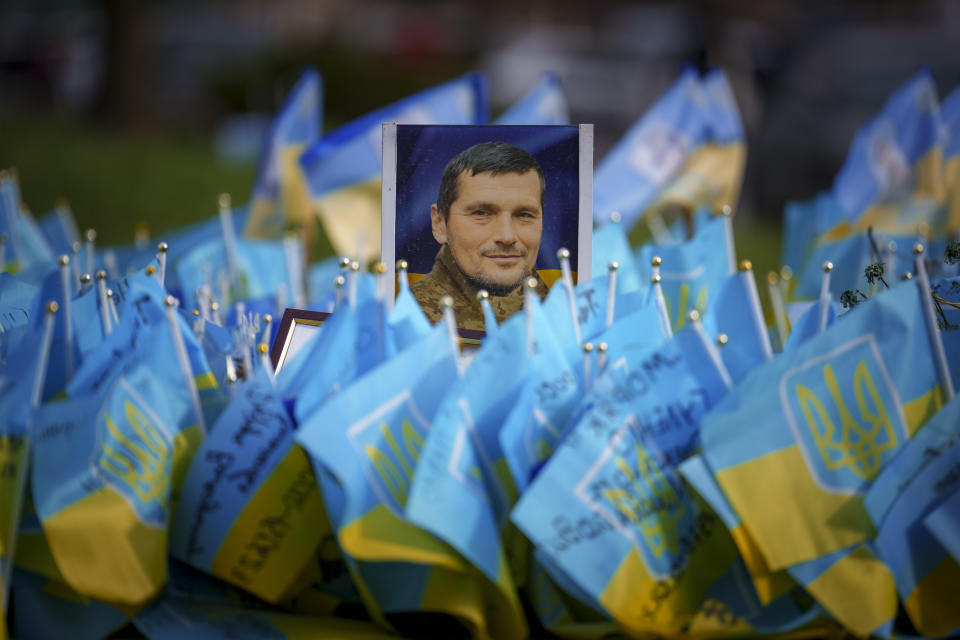 A photograph of a fallen Ukrainian serviceman is placed at a memorial in Independence Square, in Kyiv, Ukraine, Wednesday, April 3, 2024. Ukraine on Wednesday lowered the military conscription age from 27 to 25 in an effort to replenish its depleted ranks after more than two years of war following Russia's full-scale invasion. (AP Photo/Vadim Ghirda)