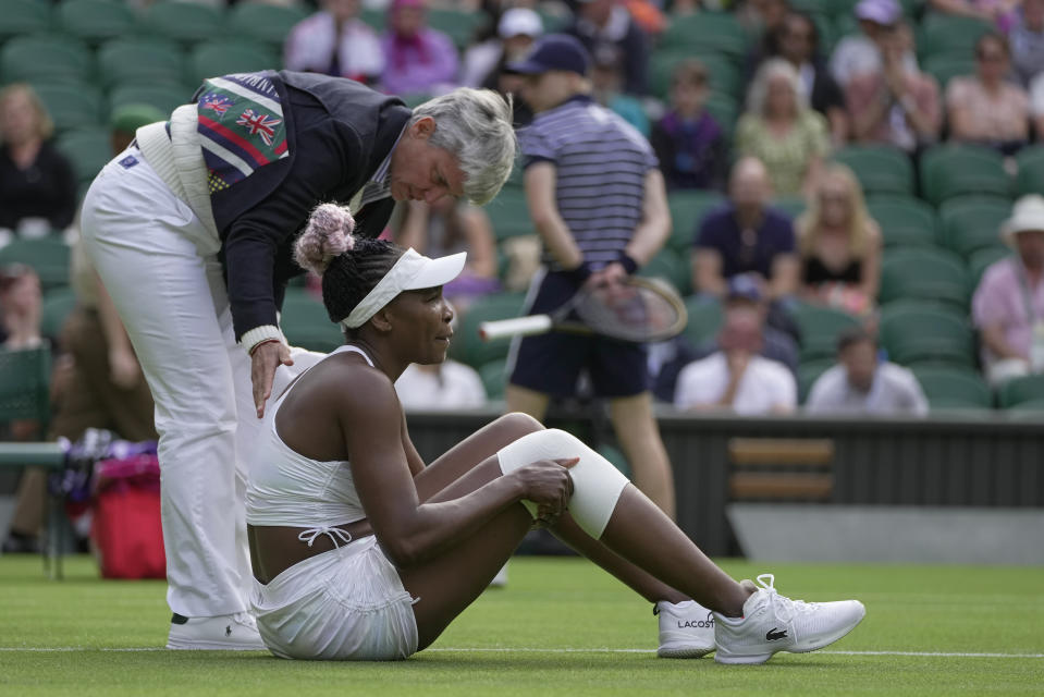 Officials assist after Venus Williams of the US slipped as she plays Ukraine's Elina Svitolina in a first round women's singles match on day one of the Wimbledon tennis championships in London, Monday, July 3, 2023. (AP Photo/Kin Cheung)
