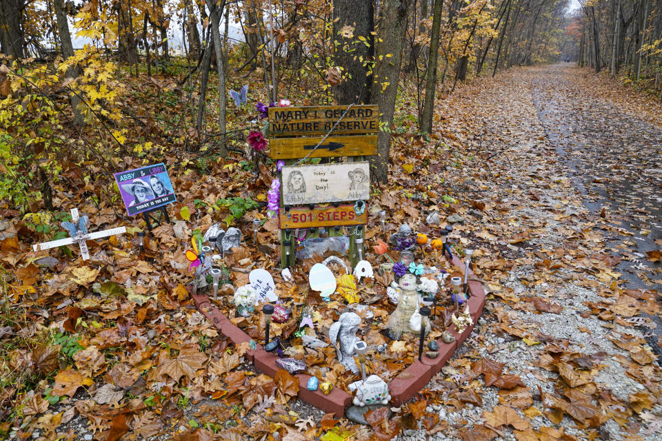 FILE - A makeshift memorial to Liberty German and Abigail Williams is pictured near where they were last seen and where the bodies were discovered along the Monon Trail leading to the Monon High Bridge Trail in Delphi, Ind., Oct. 31, 2022. An Indiana judge said Tuesday, Nov. 22, that she will decide soon whether to unseal court records that led to a man’s arrest in the 2017 killings of the two teenage girls, while a prosecutor urged the court to keep the documents sealed because others could be involved in the case. (AP Photo/Michael Conroy, File)