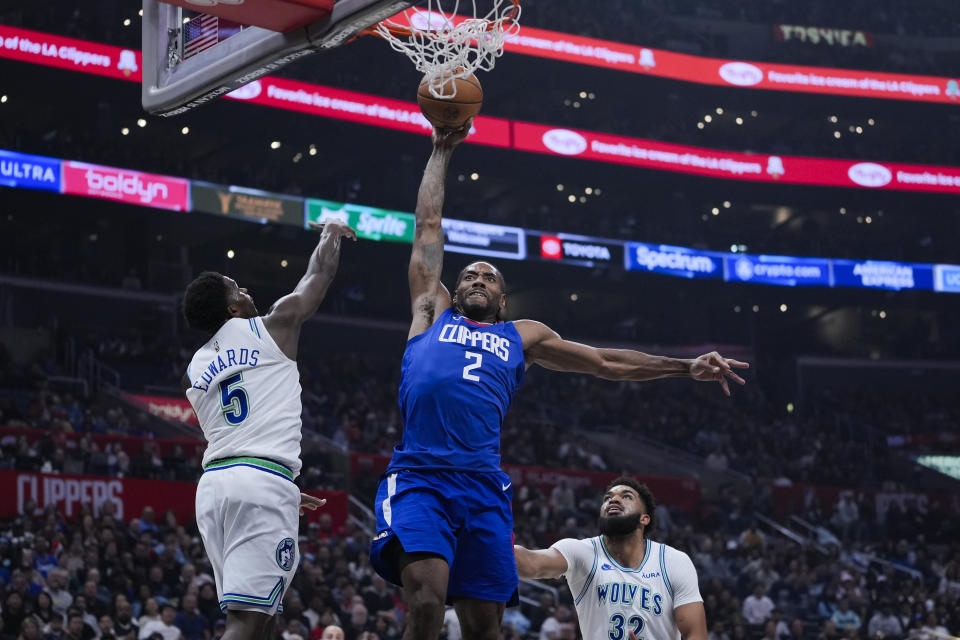 Los Angeles Clippers forward Kawhi Leonard, center, dunks the ball past Minnesota Timberwolves guard Anthony Edwards, left, and center Karl-Anthony Towns during the first half of an NBA basketball game, Monday, Feb. 12, 2024, in Los Angeles. (AP Photo/Ryan Sun)