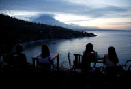 <p>Tourists have a drink while watching the sunset behind Mount Agung, a volcano on the highest alert level, in Amed on the resort island of Bali, Indonesia on Sept. 25, 2017. (Photo: Darren Whiteside/Reuters) </p>