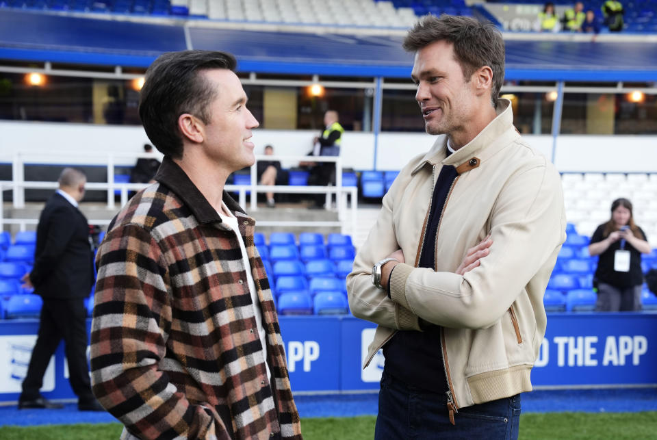 Wrexham co-owner Rob McElhenney, left, and Birmingham City co-owner Tom Brady speak before a Sky Bet League One soccer match in Birmingham, England, Monday Sept. 16, 2024. (Nick Potts/PA via AP)