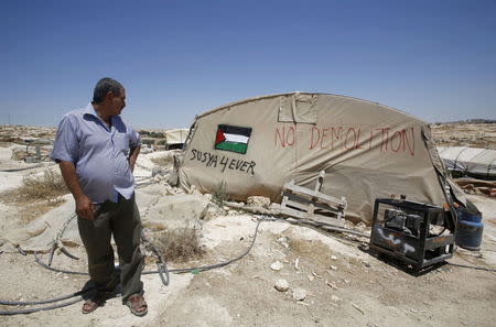 Palestinian man Jihad Nuwaja stands next to a tent in Susiya village, south of the West Bank city of Hebron July 20, 2015. REUTERS/Mussa Qawasma