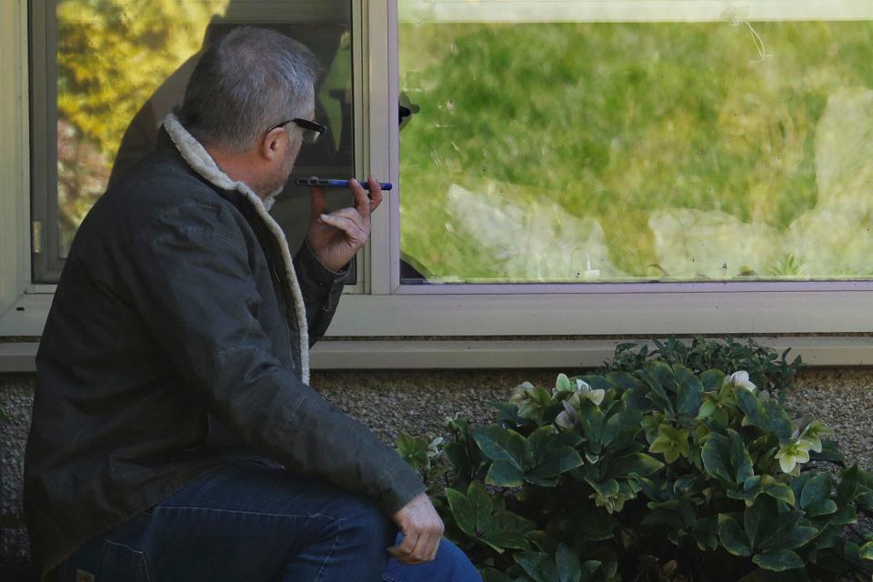 Marty Shape, left, talks to his mother, Judy Shape, on the phone as they look at each other through her window on Monday at the Life Care Center near Seattle. In-person visits are not being allowed at the nursing home at the center of the state's coronavirus outbreak.