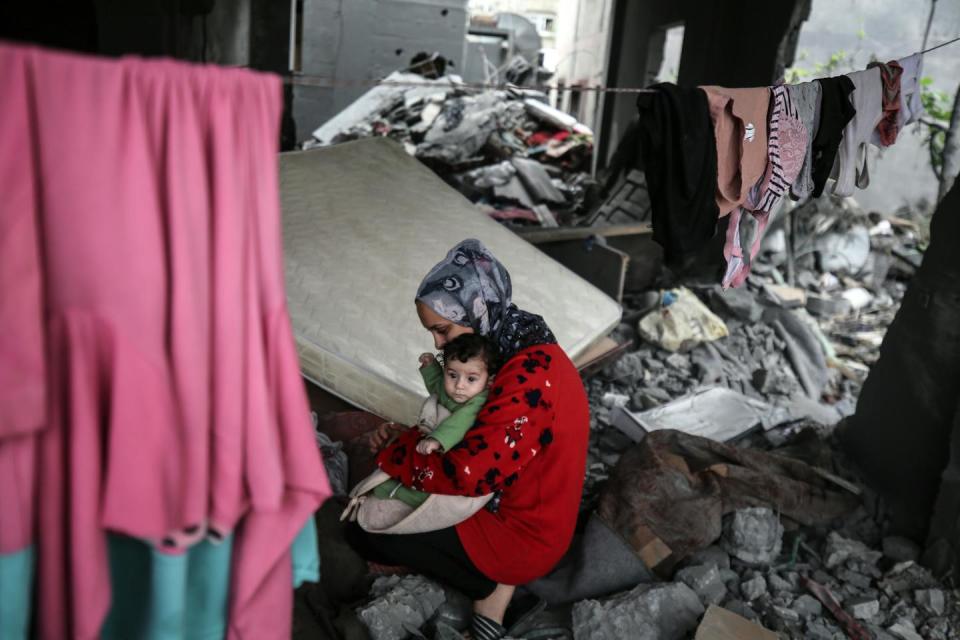 A Palestinian woman holds her baby at her home destroyed by Israeli air strikes in a central area of the Gaza Strip on Nov. 15, 2023. <a href="https://www.gettyimages.com/detail/news-photo/palestinian-woman-holds-her-baby-at-her-home-destroyed-news-photo/1783907050?adppopup=true" rel="nofollow noopener" target="_blank" data-ylk="slk:Majdi Fathi/NurPhoto via Getty Images;elm:context_link;itc:0;sec:content-canvas" class="link ">Majdi Fathi/NurPhoto via Getty Images</a>