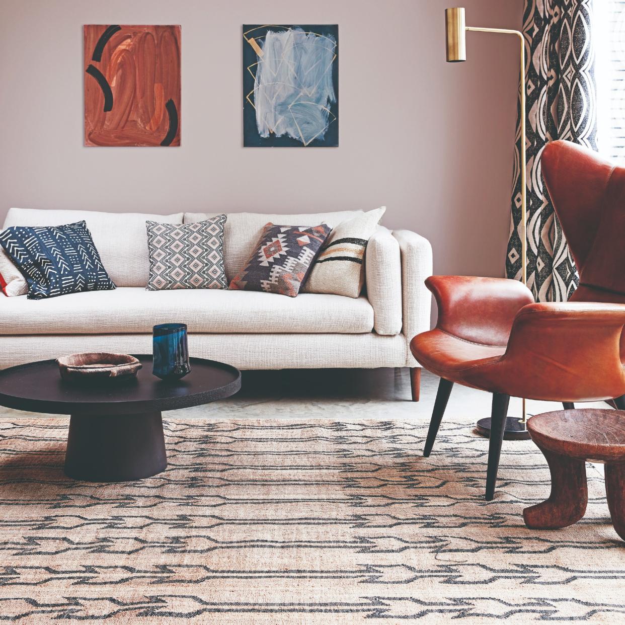 A pink-painted living room with a cream sofa and a patterned rug. 