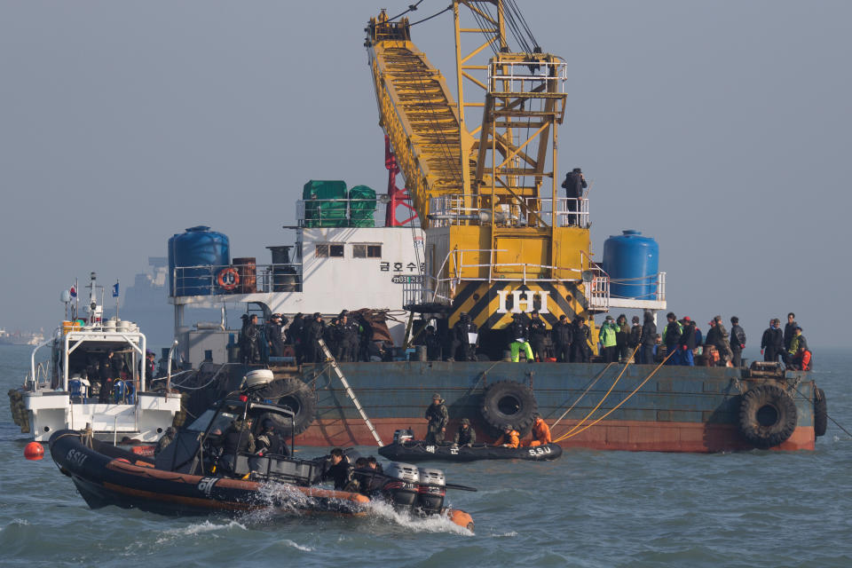 In this Tuesday, April 22, 2014, searchers and divers look for people believed to have been trapped in the sunken ferry Sewol in the water off the southern coast near Jindo, south of Seoul, South Korea. One by one, coast guard officers carried the newly arrived bodies covered in white sheets from a boat to a tent on the dock of this island, the first step in identifying a sharply rising number of corpses from the South Korean ferry that sank nearly a week ago. (AP Photo/Korea Pool) KOREA OUT