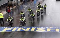 Police on bikes cycle across the Boston Marathon finish line prior to a remembrance ceremony for family members and survivors of the 2013 Boston Marathon bombing on Boylston Street in Boston, Tuesday, April 15, 2014. (AP Photo/Elise Amendola)